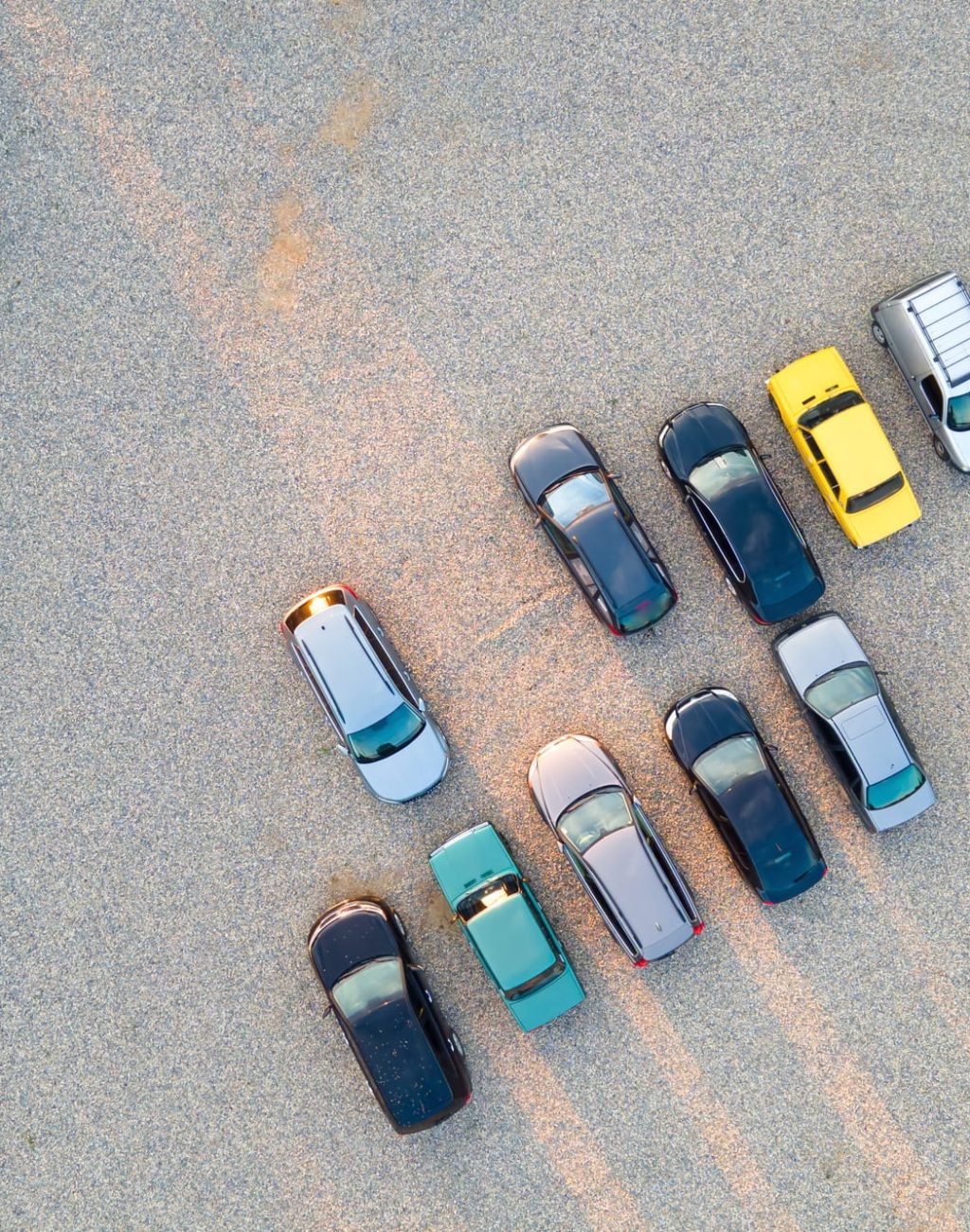 Aerial view of many colorful cars parked on parking lot in evening